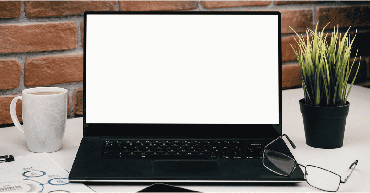 open laptop on desk against brick wall